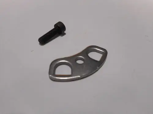 Befestigungsflansch aus Metall mit zwei Löchern und einer Öffnung, neben einer schwarzen Schraube, vermutlich für die Montage eines Remeha-Produkts.